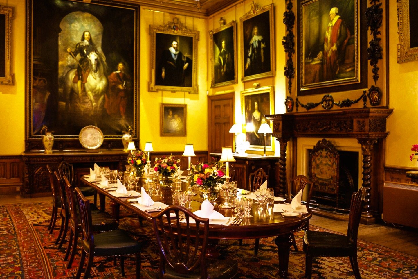 The formal dining room at Highclere Castle set for dinner beneath grand portraits